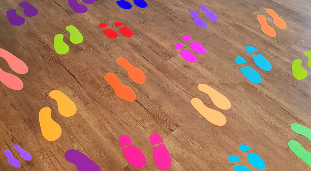 许多彩色足迹贴纸在木地板或棕色木材的背景。图片下载