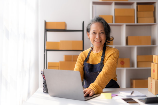 亚洲资深女性电子商务企业家，检查货物是否交付给客户，并使用笔记本电脑。图片下载