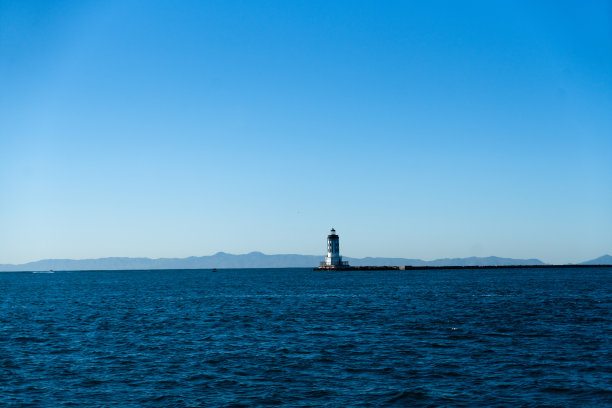 在熙熙攘攘的洛杉矶港外，一座坚固的海堤的尽头，矗立着一座坚固的灯塔，它的灯塔在变幻莫测的海面上投下指路的光芒。图片下载