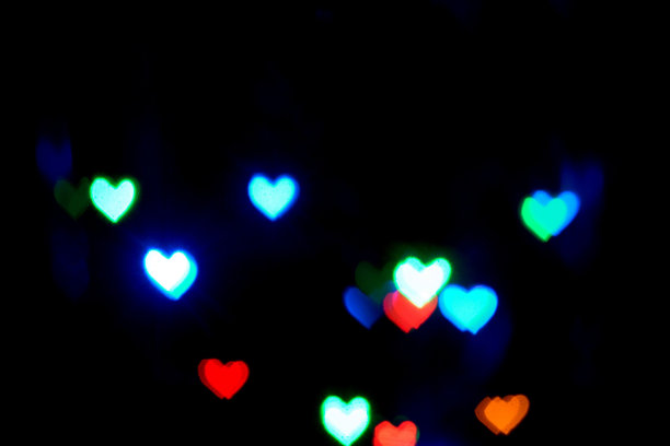 在黑暗中，心形的多色模糊灯光。图片下载