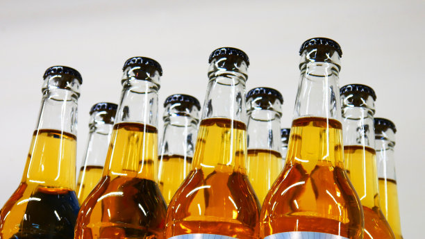 在白色的背景下，许多漂亮的玻璃瓶装着金黄色的窖藏啤酒图片下载