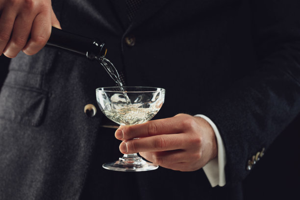 一个人把香槟酒倒进杯子里。图片下载