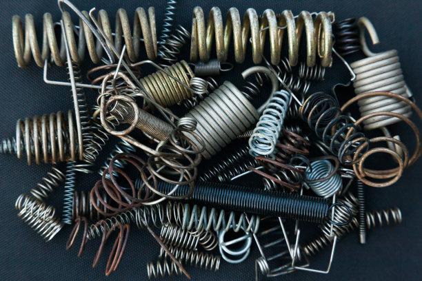 许多大小不一的小弹簧在黑色的背景下堆成一堆。图片下载