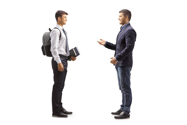 一名年轻男子与一名穿着校服的男学生交谈的全身侧面照图片下载