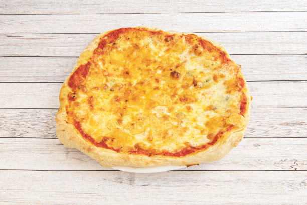 白色木桌上的小披萨，有四块融化的奶酪和西红柿图片下载