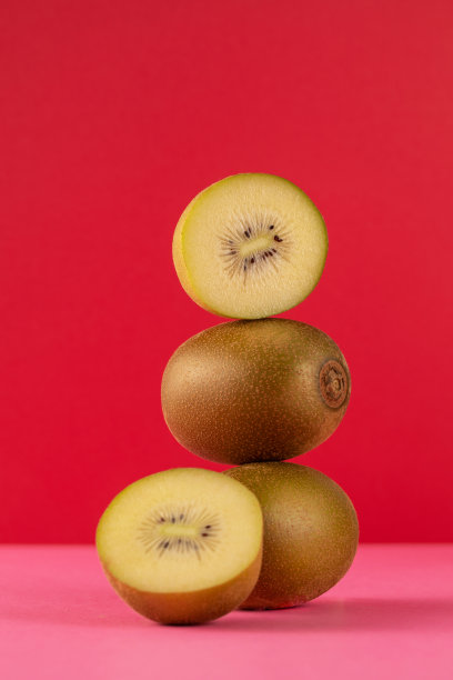 在红色背景上平衡金色猕猴桃的静物。水果的概念图片下载