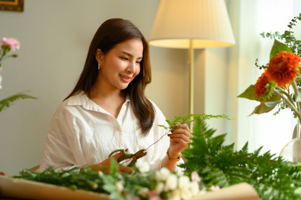 年轻的成年女性小企业主剪树枝，创造美丽的花束她的花店。图片下载