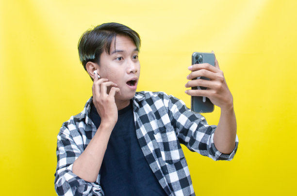 快乐的富有表现力的亚洲人使用耳机，从手机上享受音乐图片下载