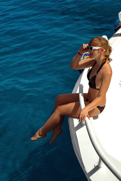 身穿比基尼的金发女子在豪华游艇上享受日光浴图片下载