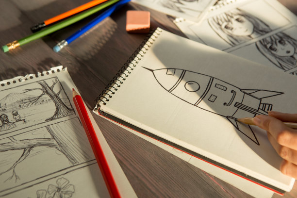 艺术家在工作室里画动漫漫画书。木桌，自然光。创意和灵感的概念。图片下载