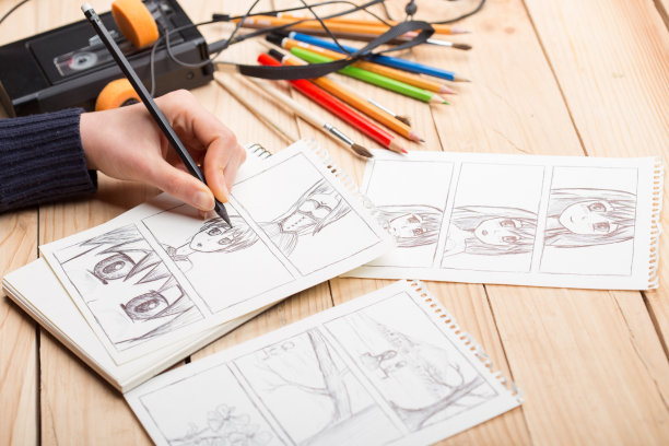艺术家在工作室里画动漫漫画书。木桌，自然光。创意和灵感的概念。图片下载