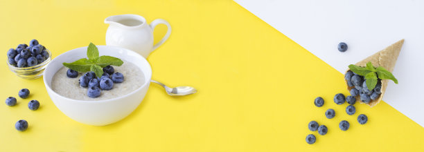 牛奶燕麦片，白碗里的蓝莓，黄色背景上的甜筒冰激凌。副本的空间。图片下载