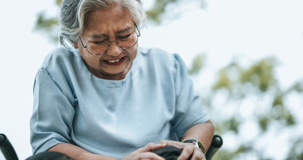 坐轮椅的成熟女性膝盖疼痛，脸上有疼痛的表情图片下载