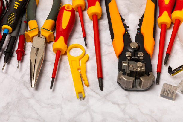 电工工具，白色大理石背景。万用表，施工胶带，电工胶带，螺丝刀，钳子，自动绝缘剥离器，插座和LED灯。弗拉特利。电工概念。工具箱。图片下载