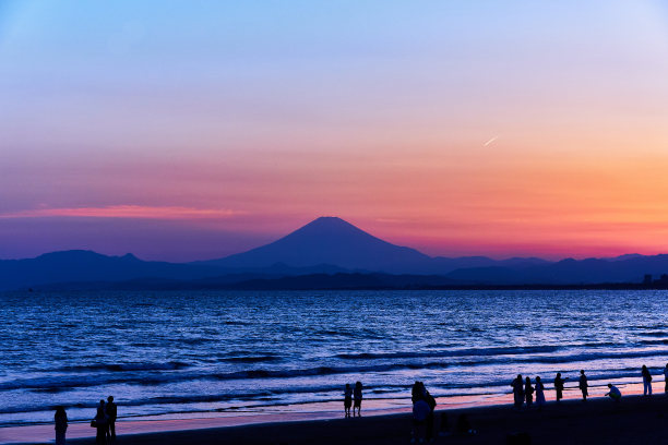 风景秀丽的海洋与剪影的人站在阴晴不定的天空在日落图片下载