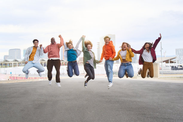 兴奋的多元文化朋友在城市街道上手拉手跳跃。把不同的年轻人聚集在一起。图片下载