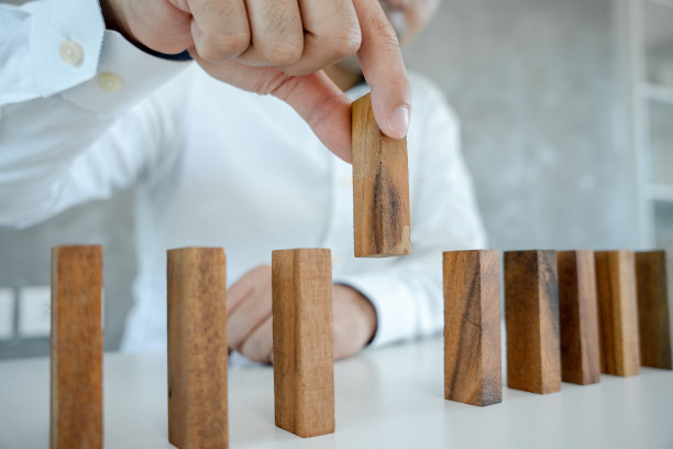 保险手里拿着多米诺骨牌。商人手中的多米诺骨牌在商业危机中倒下。经营风险的控制和防范经营保险业务的规划与策略。图片下载