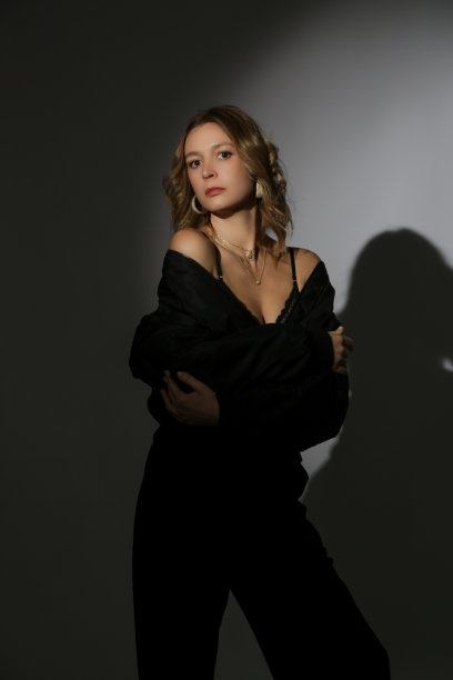 美丽的女模特在聚光灯下穿着黑色飞行员夹克和裤子的时尚肖像。女性美，时尚魅力的理念。图片下载