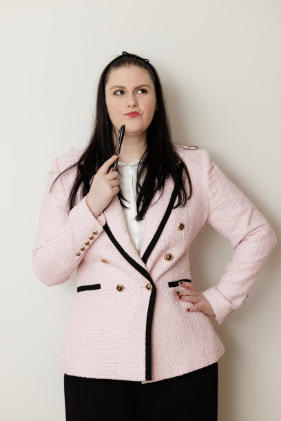 拿着笔，穿着粉色夹克的不开心的女商人图片下载