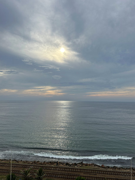 日落天空在海上的图像，空的海岸线(南线)铁路线平行于海岸线，金属铁路轨道和砾石，斯里兰卡科伦坡，重点在前景图片下载