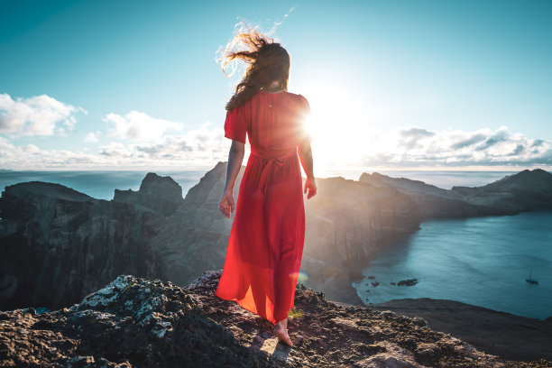一位穿着红裙子的赤脚妇女在火山岛和大西洋的山脚下欣赏日出。欧洲葡萄牙马德拉岛的<s:1> o loureno。图片下载