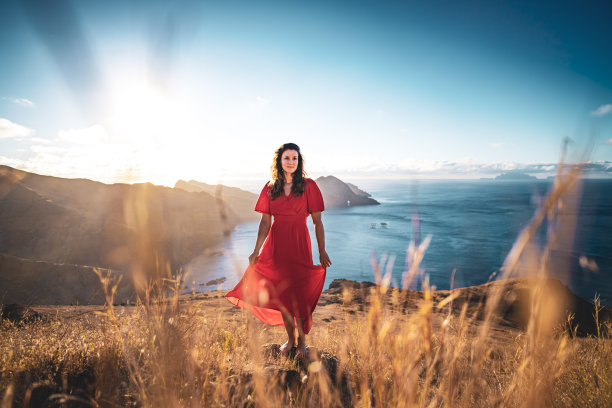 一名身穿红裙的女子站在黄色的田野上，享受着大西洋一座火山岛上清晨的空气。欧洲葡萄牙马德拉岛的<s:1> o loureno。图片下载