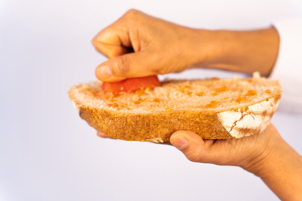 用手在面包片上挤西红柿的特写，这是地中海风格的传统手势，用橄榄油。图片下载