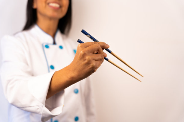 微笑的拉丁女厨师示范如何用东方风格的筷子吃饭。图片下载