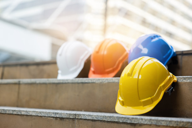 建筑工人，工程师，技术人员，在建筑工地工作的检查员的头盔。工作时戴上安全帽，防止事故发生。蓝领工人的工作设备-库存照片图片下载