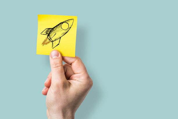 一只手展示着粘在便条上的火箭图片下载