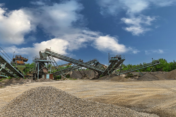 破碎机械，圆锥式岩石破碎机，在采石场露天采矿中输送破碎的花岗岩砾石。采矿行业采石输送机。图片下载