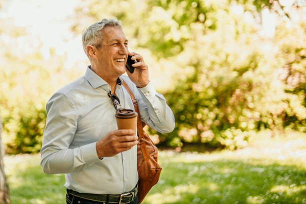 成熟的商人边走边喝咖啡边打电话图片下载