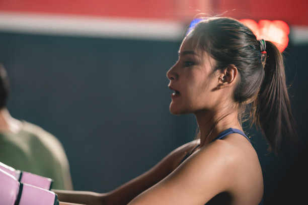 年轻健康的女运动员和运动员，戴着拳击手套，准备在现代健身房和俱乐部练习与伙伴和队友摔跤图片下载