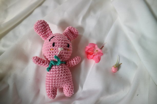 白布背景上的钩针兔子。针织玩具，手工制作，针线活，小兔子。图片下载