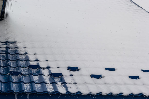 雪落在一座欧洲房子的红棕色金属瓦屋顶上图片下载