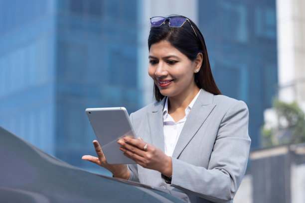 快乐的女商人拿着电子平板电脑在办公大楼外图片下载