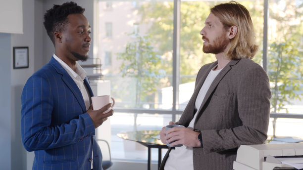 两个年轻的男性同事在办公室喝咖啡图片下载