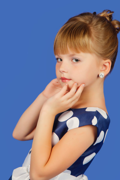 8-9岁的时尚小女孩的特写肖像，在孤立的蓝色背景下，穿着圆点裙，看着相机。漂亮的孩子在风格图像上的蓝色。时尚儿童概念。复制文本空间图片下载