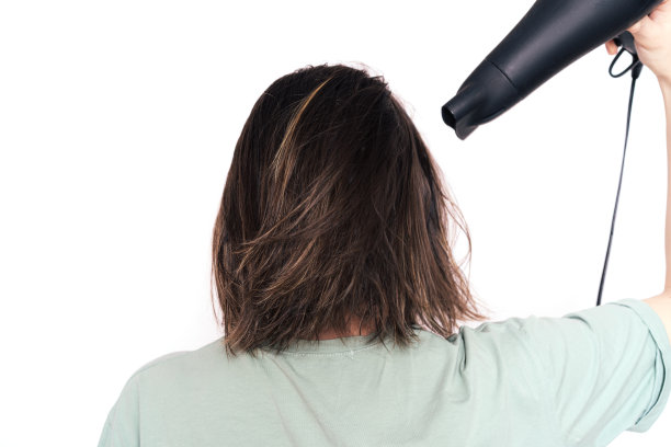 女士用吹风机在白色背景下吹干头发图片下载