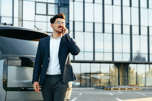穿着正装的年轻商人站在豪车旁边讲电话图片下载