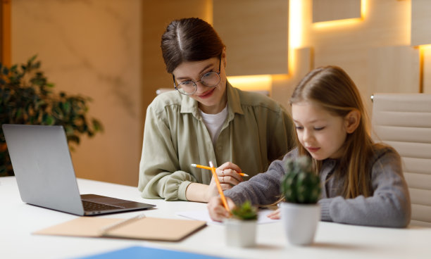 私人教师带着孩子在餐桌上做作业。图片下载