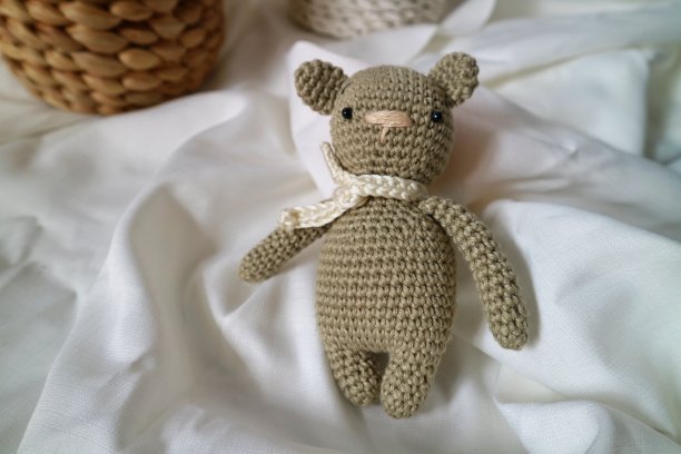 手工编织熊玩具，amigurumi。棕熊是用棉纱做成的，在白布的背景上。图片下载