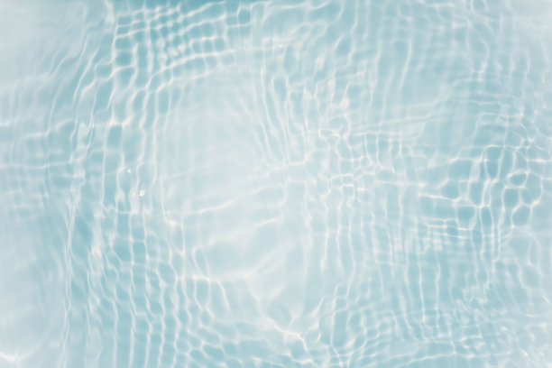 蓝蓝的水面上泛起涟漪。散焦模糊透明蓝色透明平静水面纹理与飞溅和气泡。水波与闪亮的图案纹理背景。图片下载