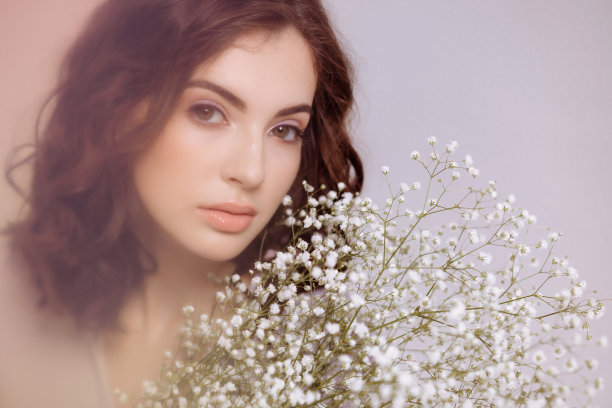 一个黑发女孩手里拿着一束吉普赛人花。图片下载