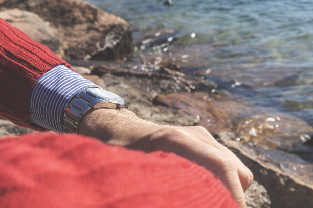 人的手和胳膊。背景是岩石和水。时间概念，放松，生活方式。副本的空间。图片下载