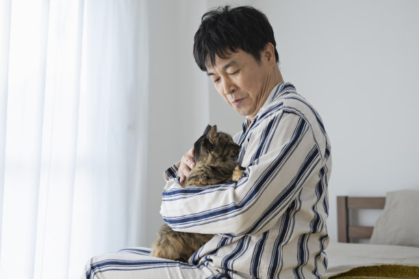 中年男子抱着猫躺在床上，早上好图片下载