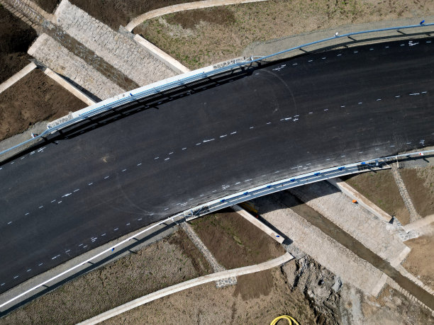 一条新建的道路，在它的一层上你可以看到连续的层的地坪和沥青地毯。周围地区被倾斜成一条带有混凝土排水沟的沟渠。雨水排水系统图片下载