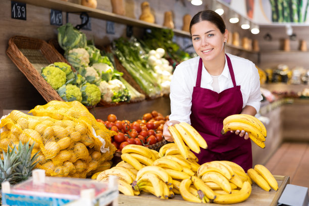 年轻的女店主正在陈列香蕉图片下载