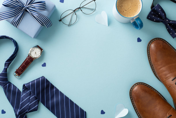 时尚的父亲节设计。顶视图平面放置组合的皮鞋，领带，领结，手表，眼镜，纸心，礼盒，咖啡杯在柔和的蓝色背景与空间复制图片下载