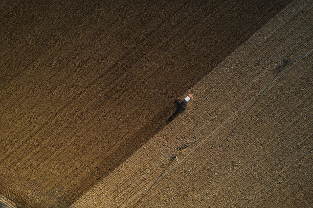 农民驾驶履带式拖拉机犁地和动力耙地，使土壤表面结皮破裂，以方便植物在干燥的土壤上生长和播种图片下载